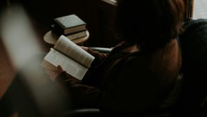 Mulher sentada confortavelmente lendo um livro, em um momento de autocuidado e presença