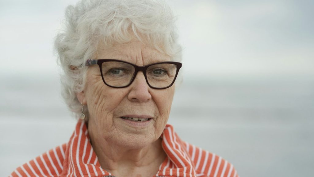 Retrato de mulher madura sorrindo, representando saúde mental e leveza na maturidade