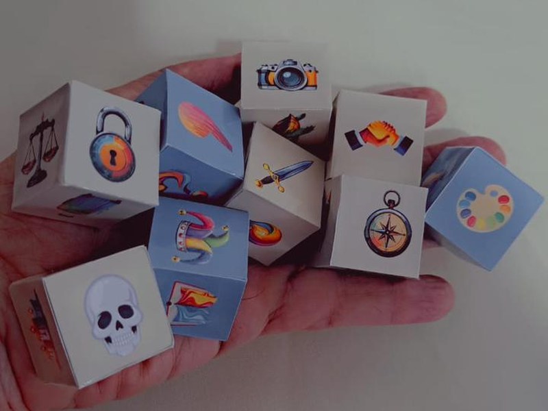 Mao segurando os cubos ilustrados do jogo Contos em Cubos
