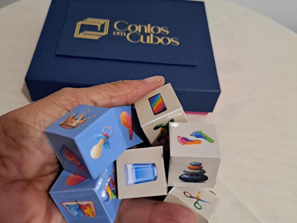 Caixa do jogo Contos em Cubos com cubos coloridos em uma mao